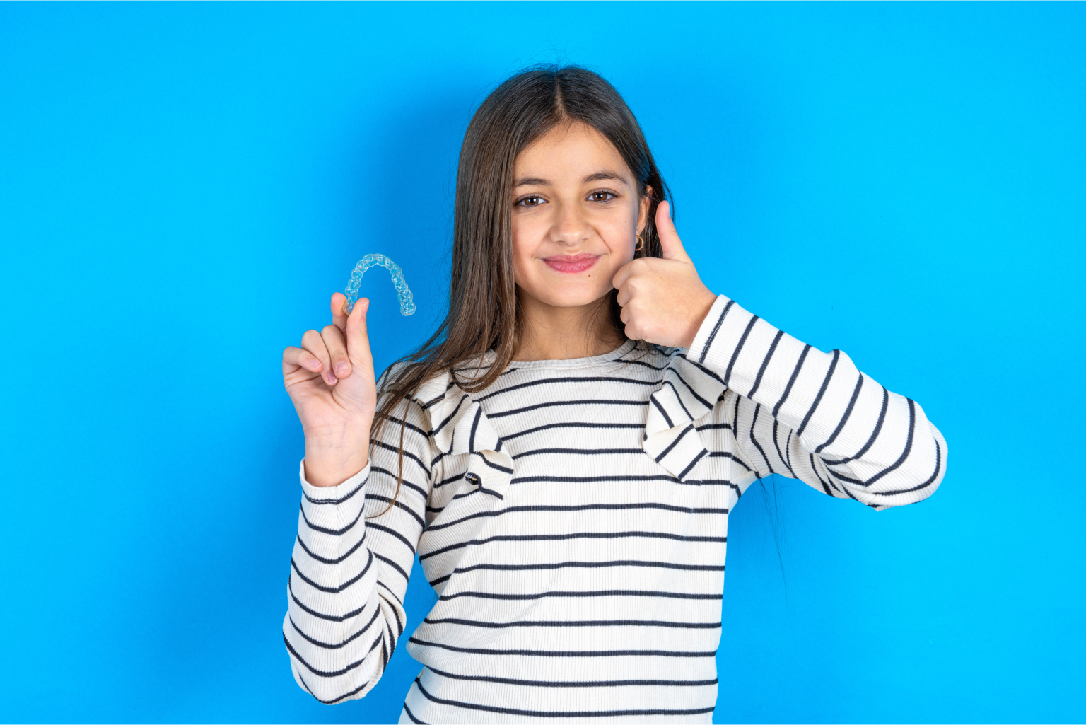 Child with clear aligner and thumbs up