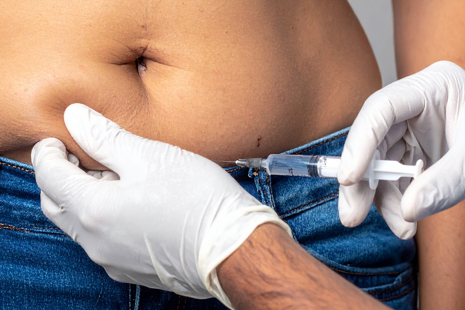 Close-up of a patient receiving a fat-dissolving injection above the belly.