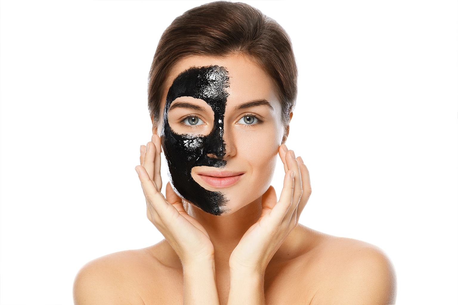 Woman undergoing carbon facial with half face covered in black carbon mask